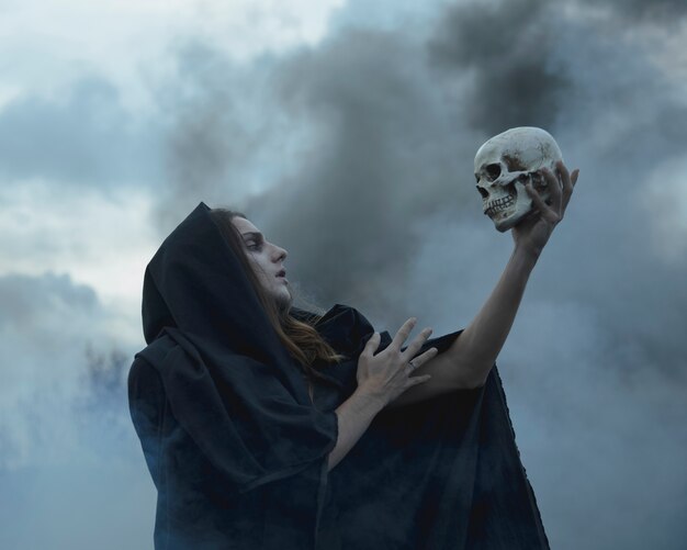 man-holding-a-skull-in-the-dark-and-looking-at-it_23-2148277542.jpg