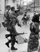A government soldier carrying two children on his back walks on a Phnom Penh street just before .jpg