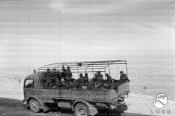 7_Un camion carico di soldati italiani avanza lungo una strada nel deserto.jpg