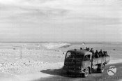 11_Un camion italiano carico di soldati avanza lungo una strada in salita nel deserto.jpg