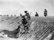 7_Una squadra di Bersaglieri in motocicletta avanza lungo una strada in una zona desertica.jpg