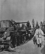 Финский солдат идет мимо разбитой советской танковой колонны.jpg