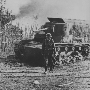 Немецкий солдат проходит мимо подбитого и сгоревшего советского танка Т-26..jpg